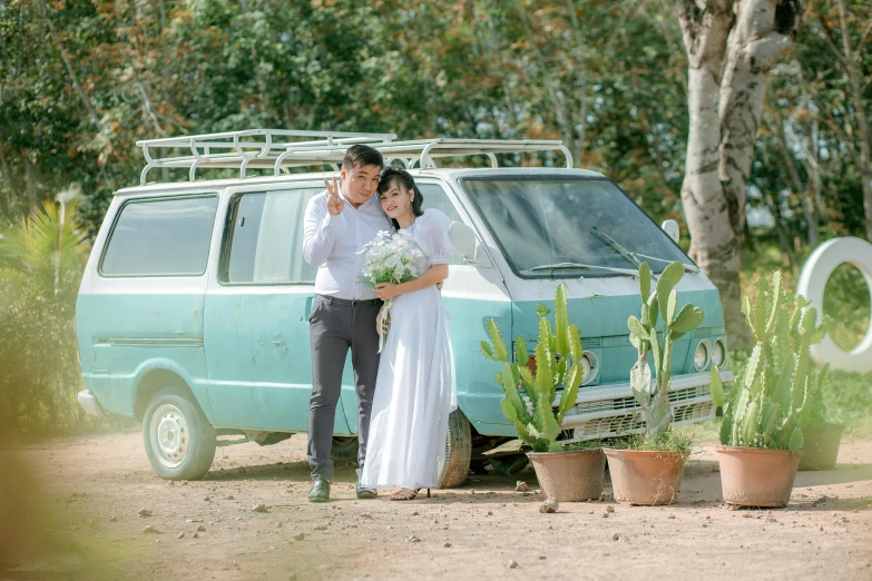 a bride and groom stand near a parked van