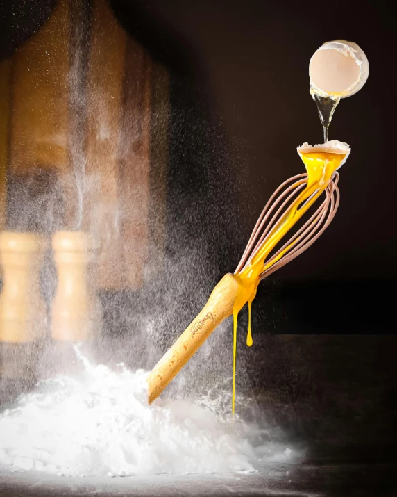 a whisk being squeezed into some kind of white substance