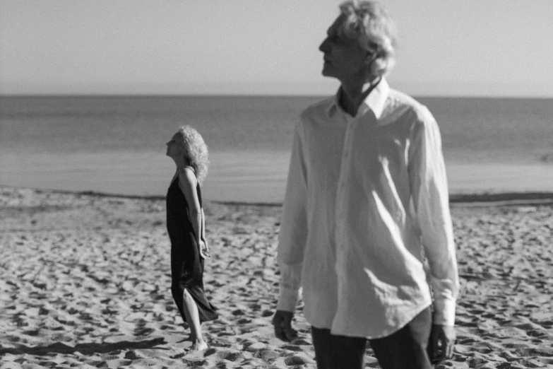 an old man and woman walk along the beach together
