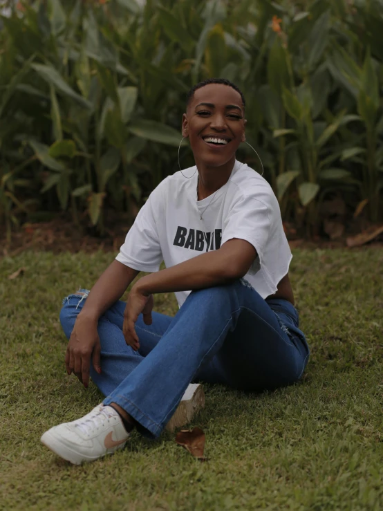 a woman smiling sitting in a field of grass