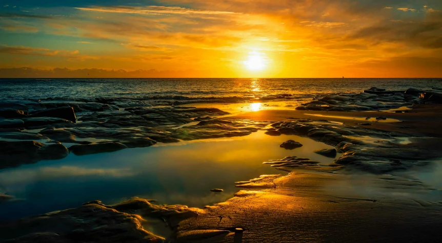 the sun sets behind a small island in the middle of the ocean