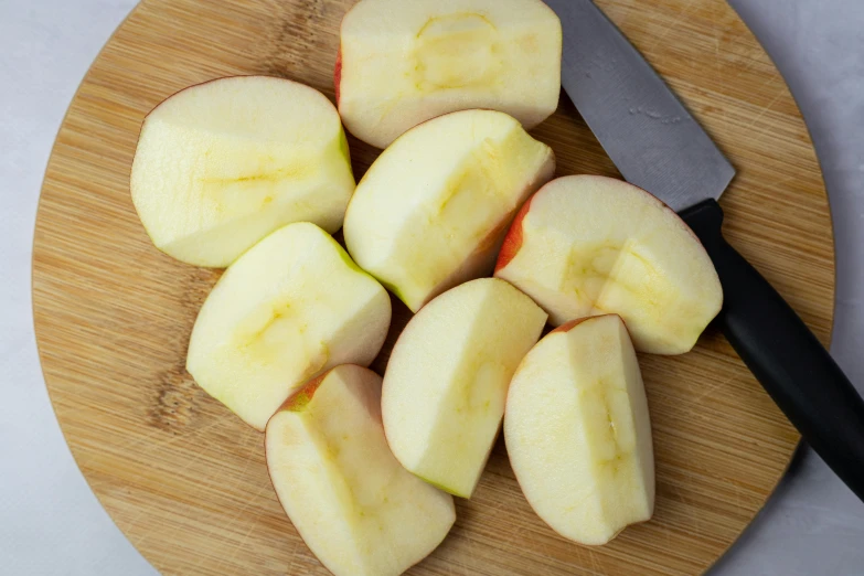 an apple sliced in slices on top of a wooden  board