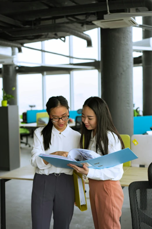 two girls reading a book in an office building