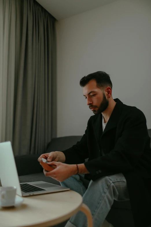 man using electronic device on a couch with windows