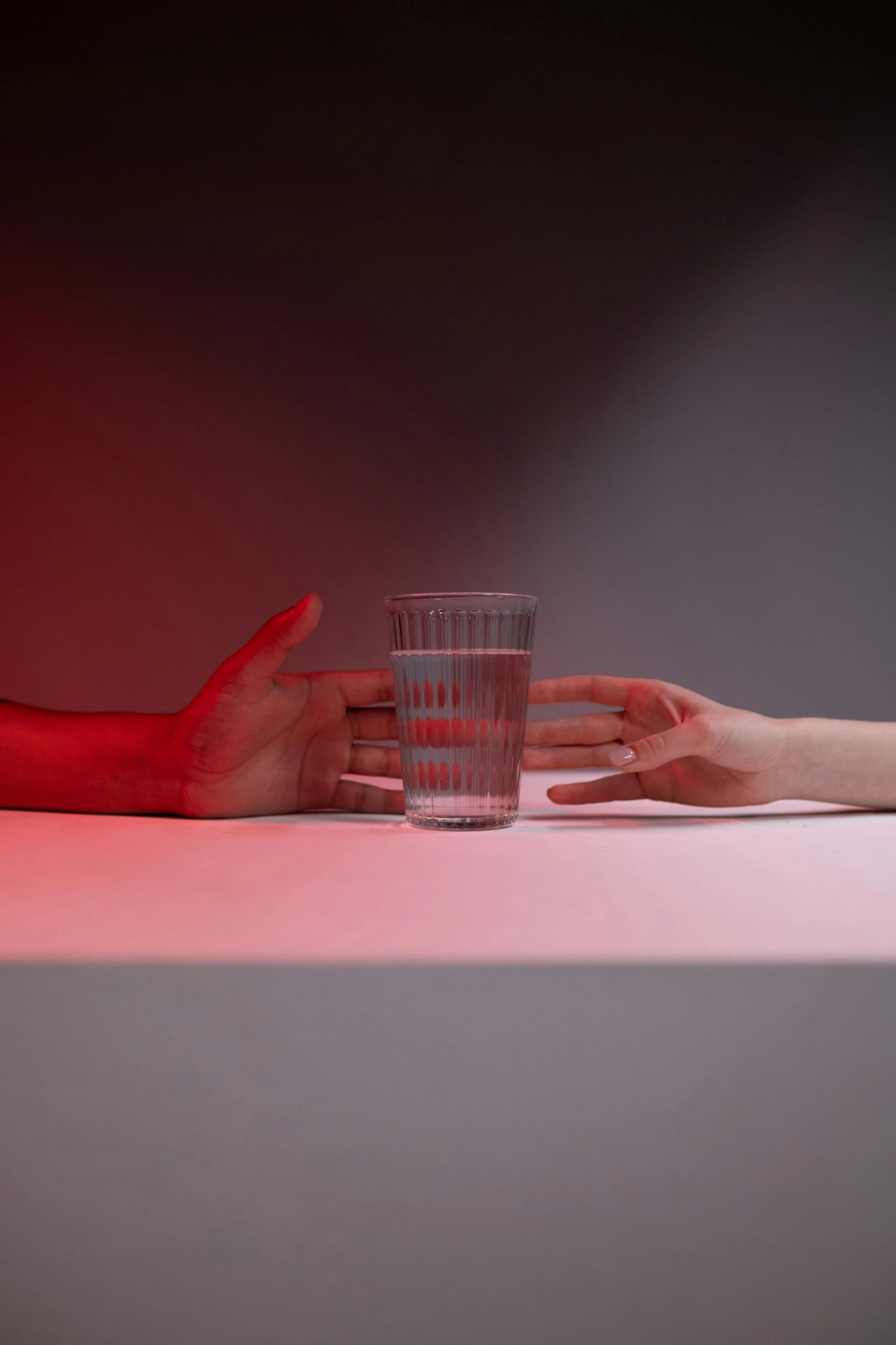 two people are touching their hands while holding a glass