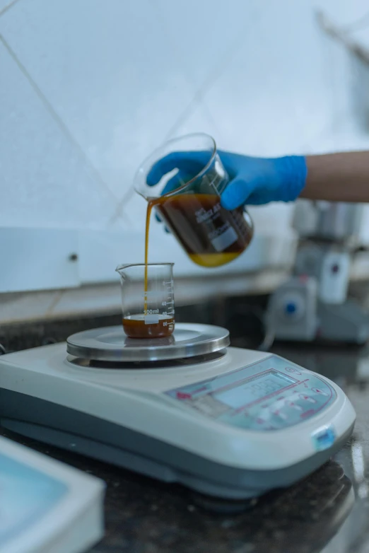 a person pouring liquid into a glass sitting on a scale