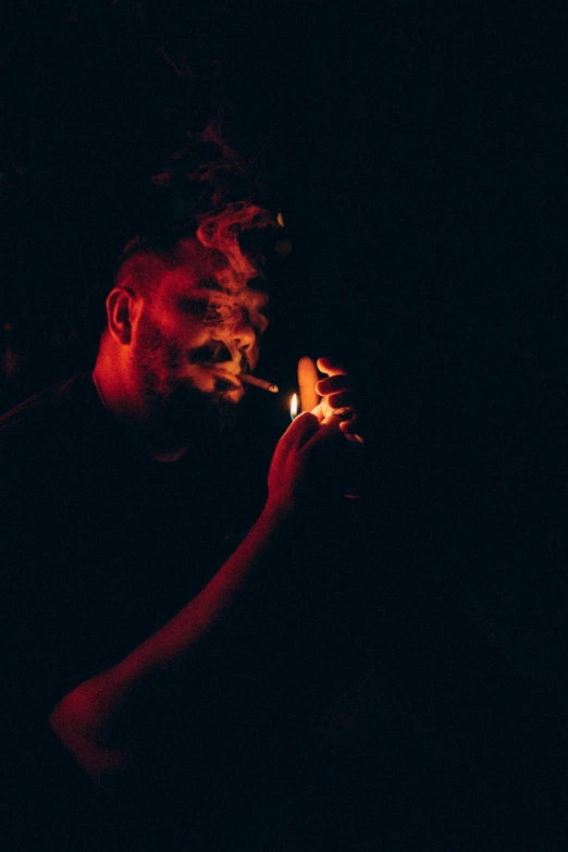 a man smokes an electronic device in the dark