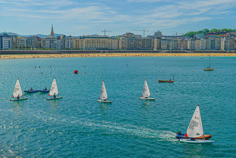 a group of sailboats in the ocean next to the shore