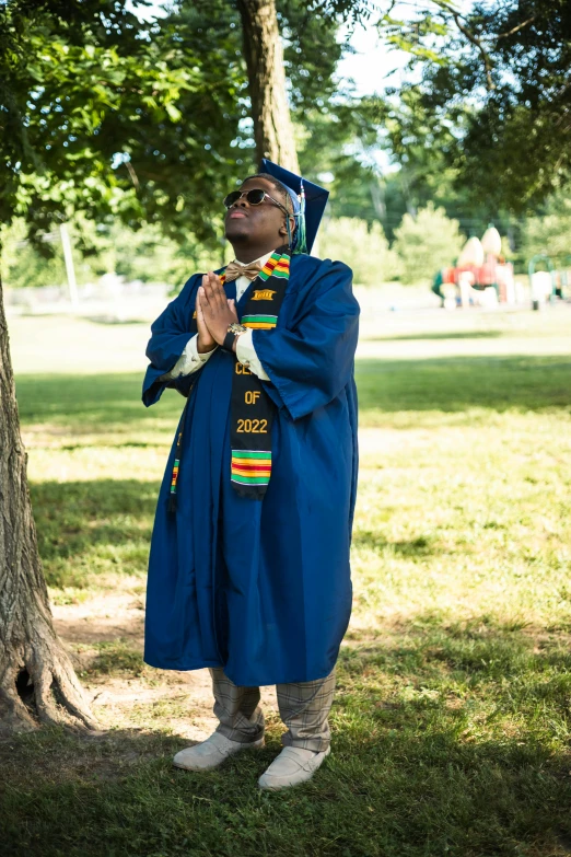 an african american man in traditional clothing is praying under a tree