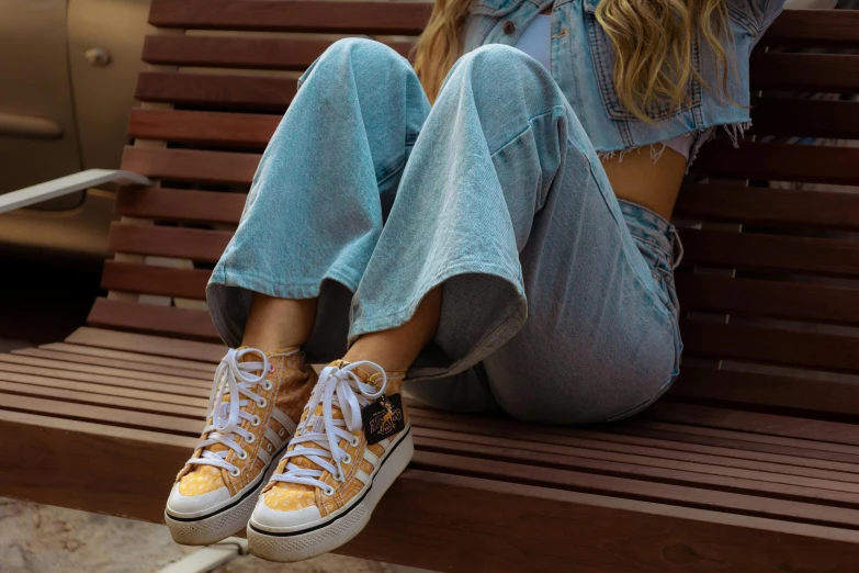 a girl sitting on a bench wearing converse sneakers