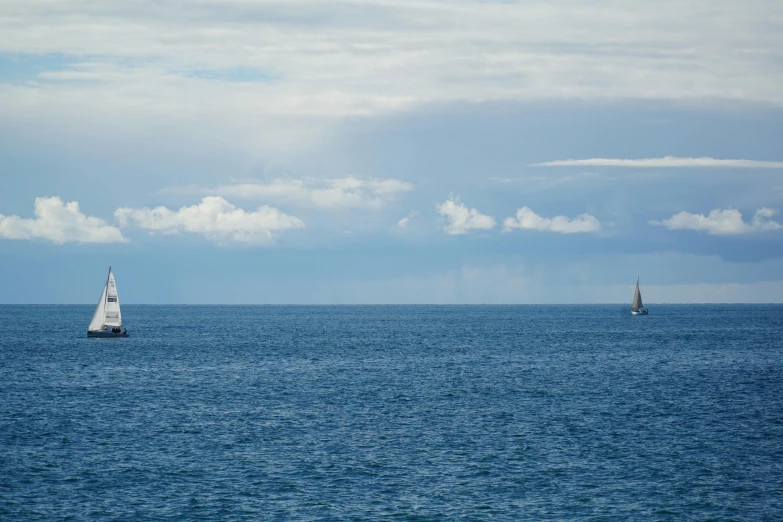 a couple of sail boats floating in the middle of the ocean