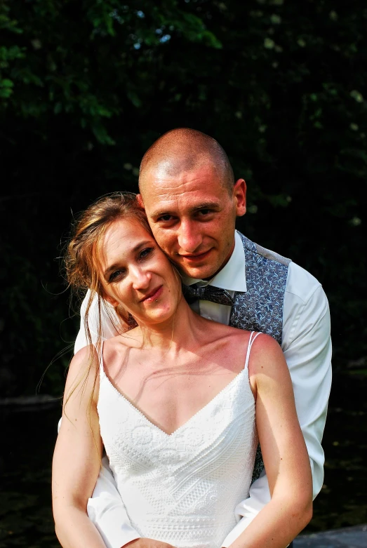 a beautiful young couple cuddling each other while standing in a wooded area