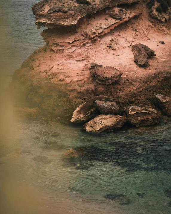 a lone bird sitting on some rocks in the water