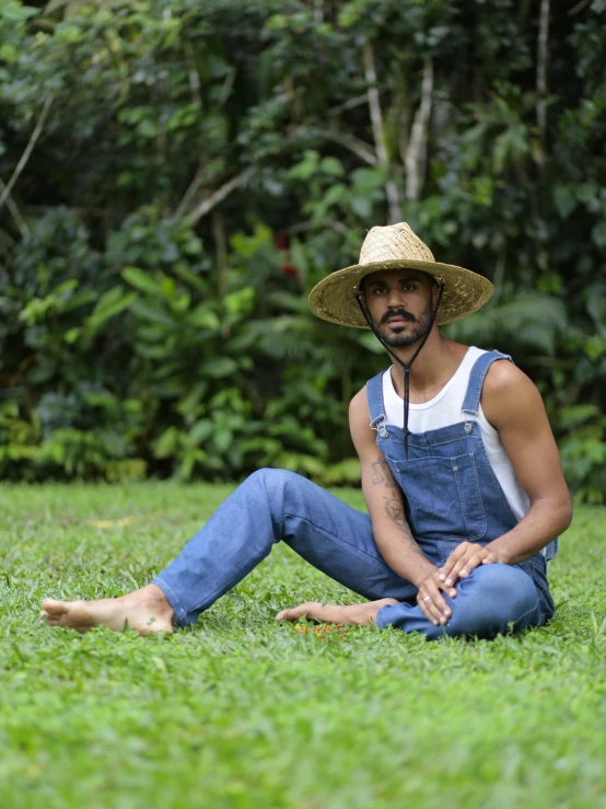 the man with a straw hat sits in the grass