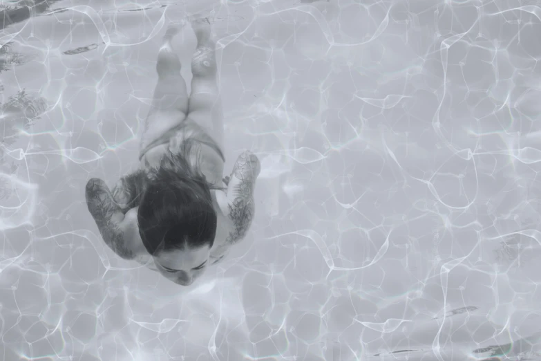 man floating in crystal clear water, top down, swimming