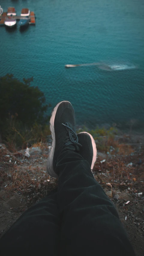 person in sneakers looking at boats in the water