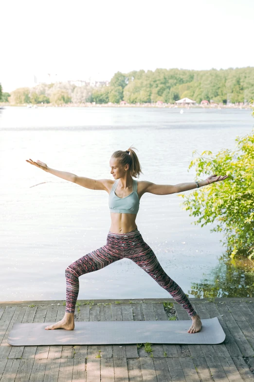 woman doing yoga on mat by the lake