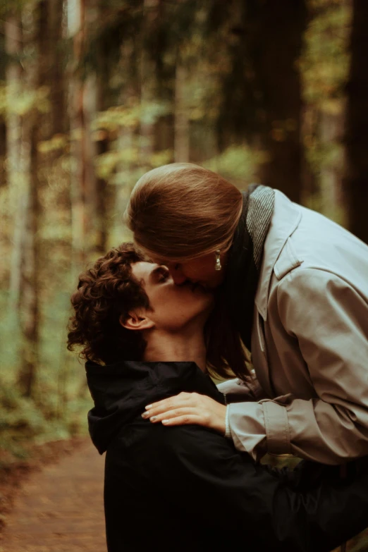 a man and a woman kiss in front of a tree