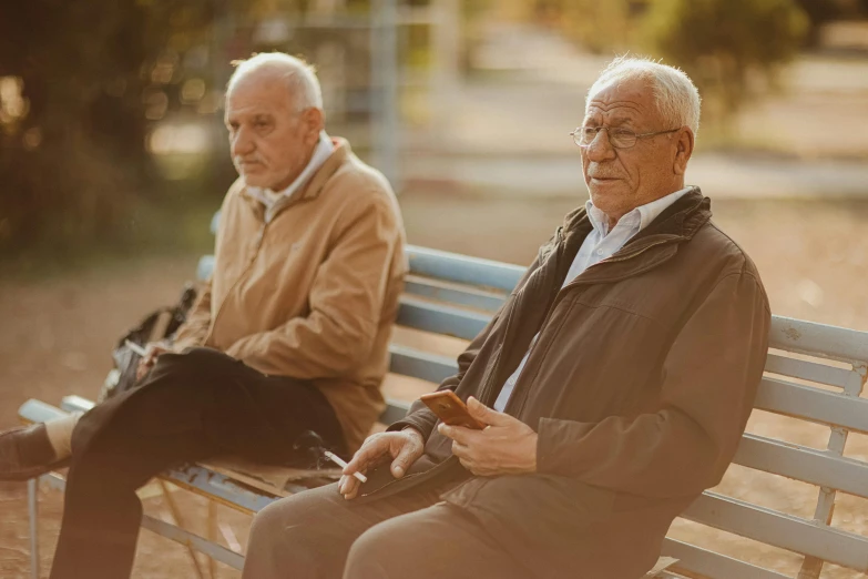 an older man sits with an old man on a park bench