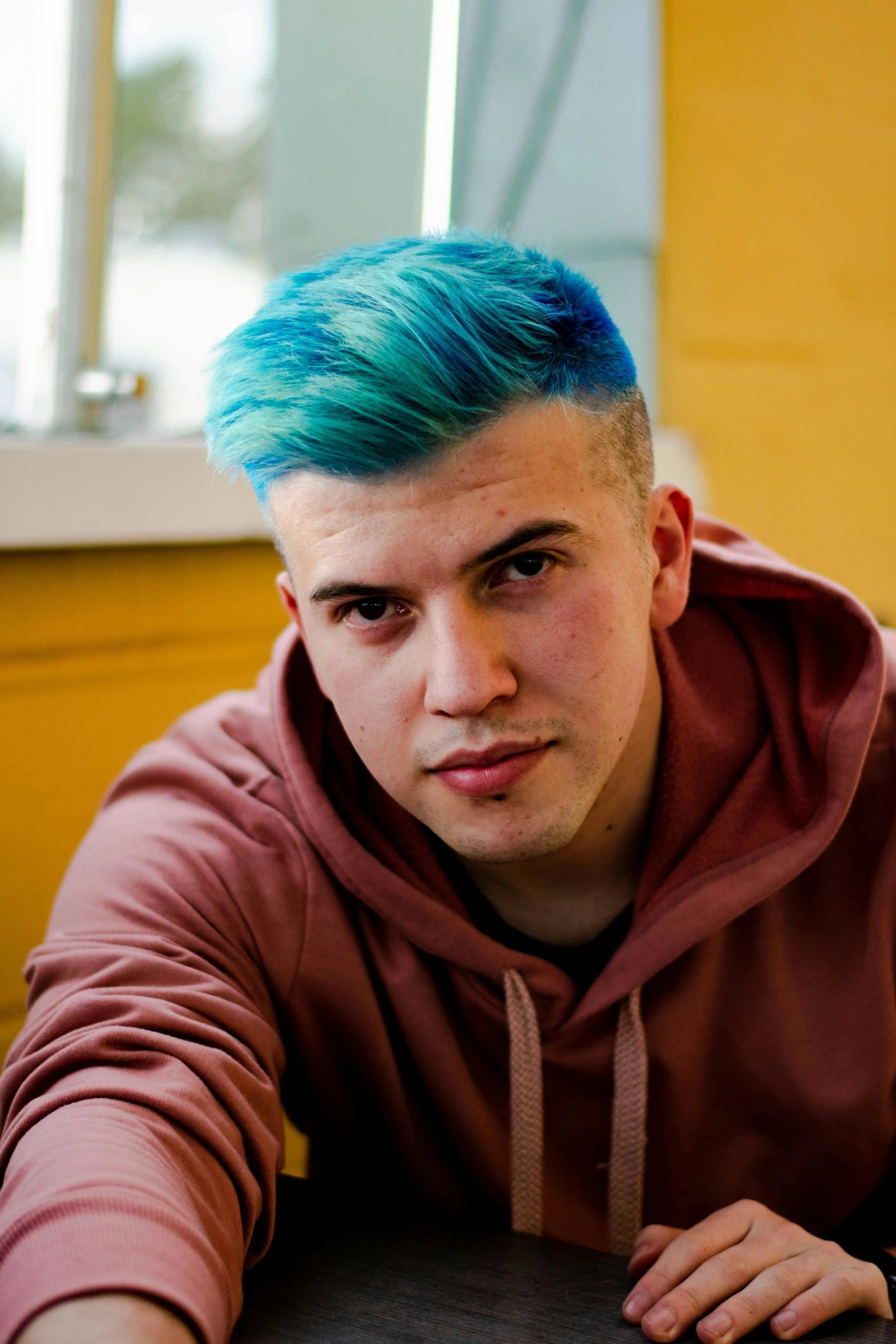 young adult male with blue hair in living room