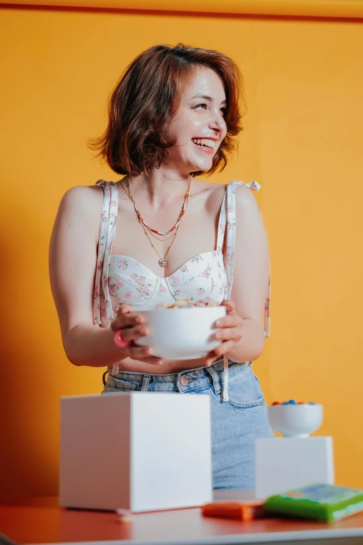 a smiling woman sitting in a chair holding a bowl