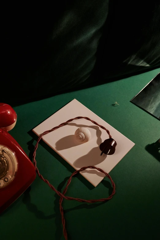 a red telephone on a green table next to an old phone