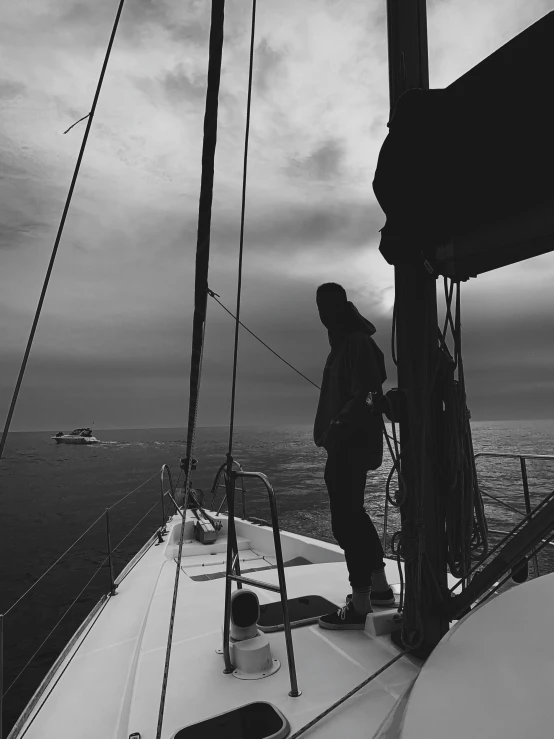 black and white pograph of a man standing on top of a boat