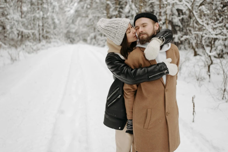 a man and woman are sharing a kiss on a snow covered road