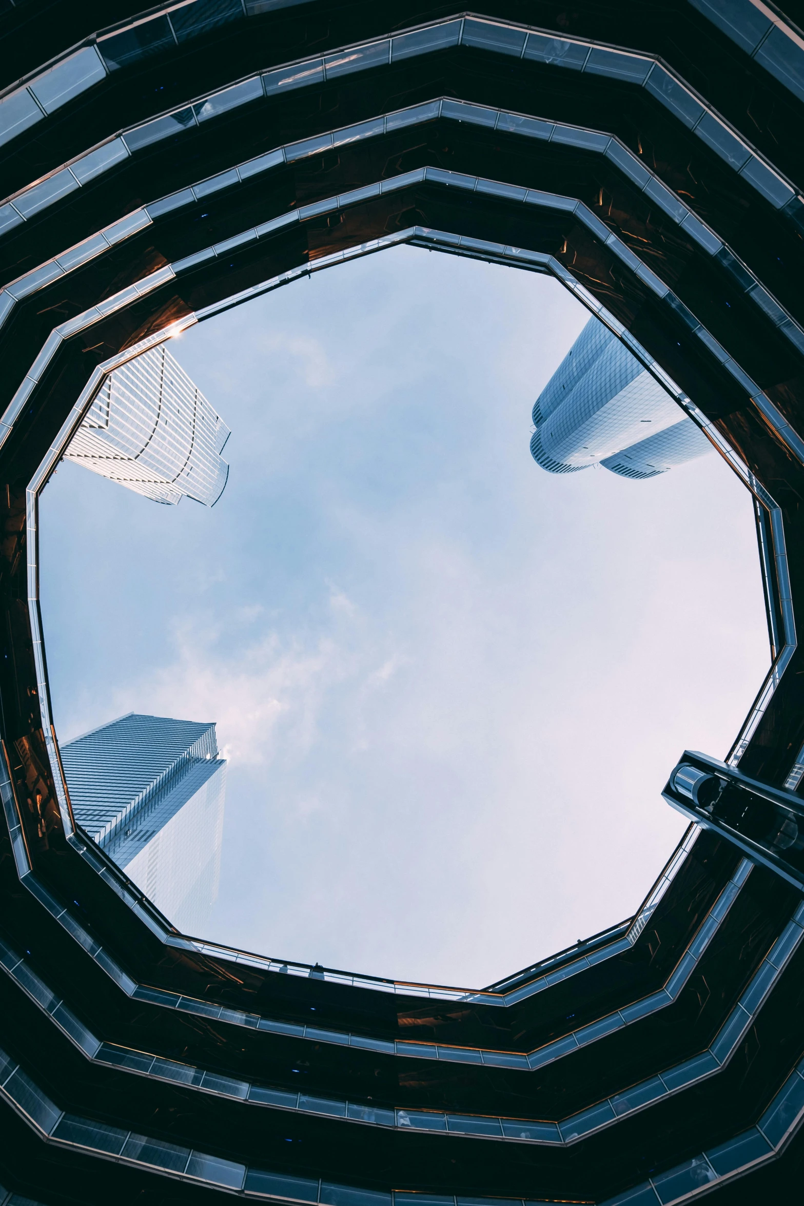 looking up at a futuristic, futuristic, circular building with sky reflected in the glass windows
