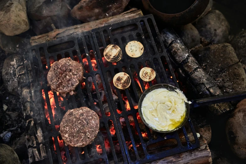 hamburgers cooking on a grill with melting sauce
