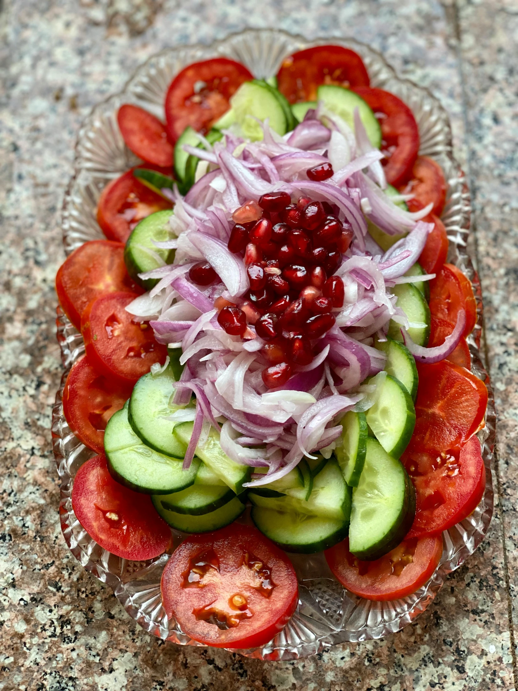 a plate with cucumber, onion and tomatoes on it