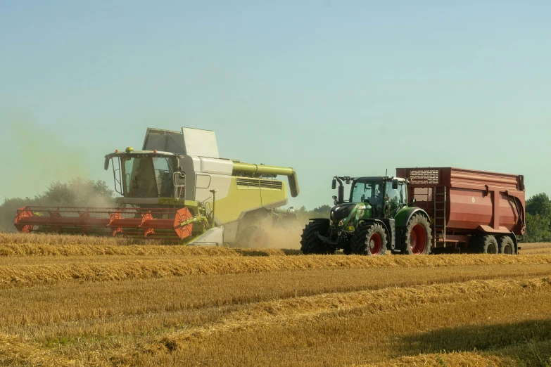 tractors plowing a grain field with two bales of seed