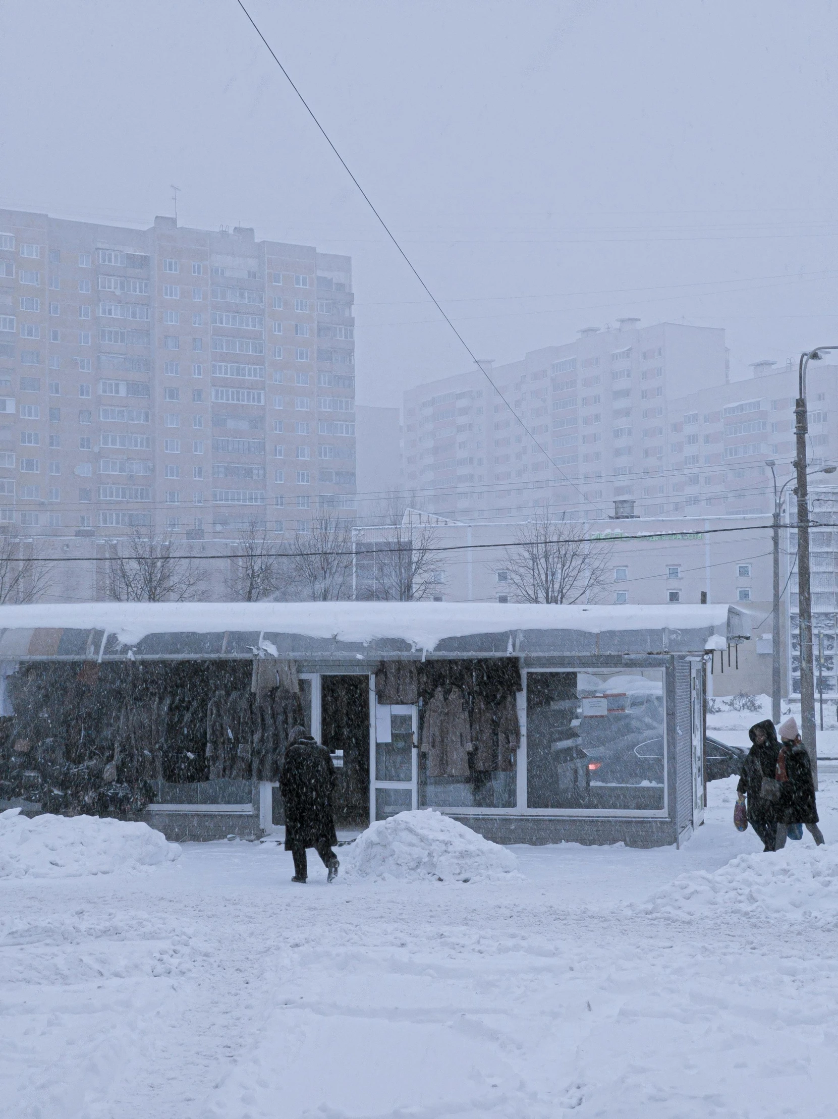 people are walking in the snow outside a bus