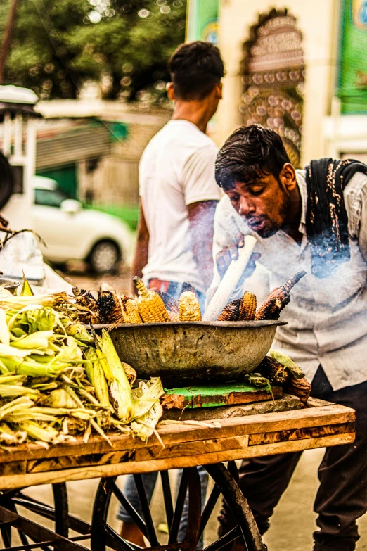 the man is selling food on his wooden cart