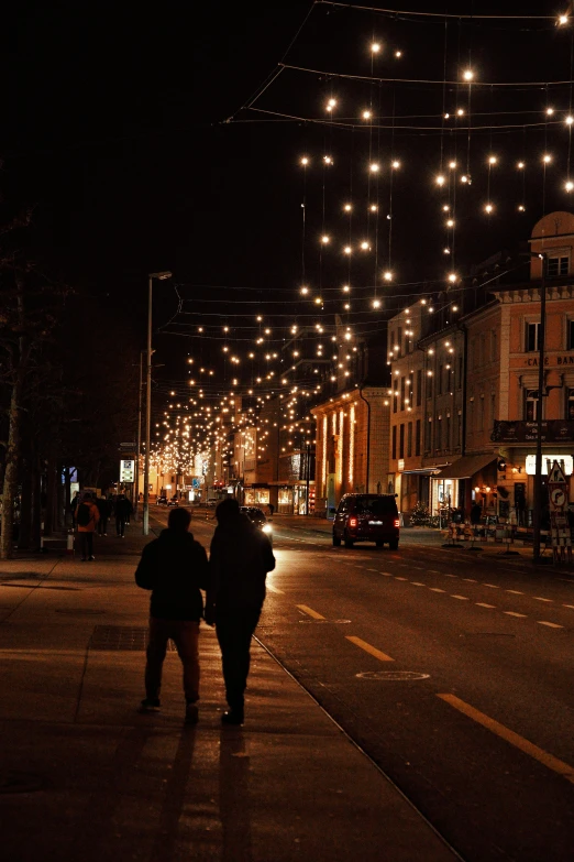 people walk down a city street at night