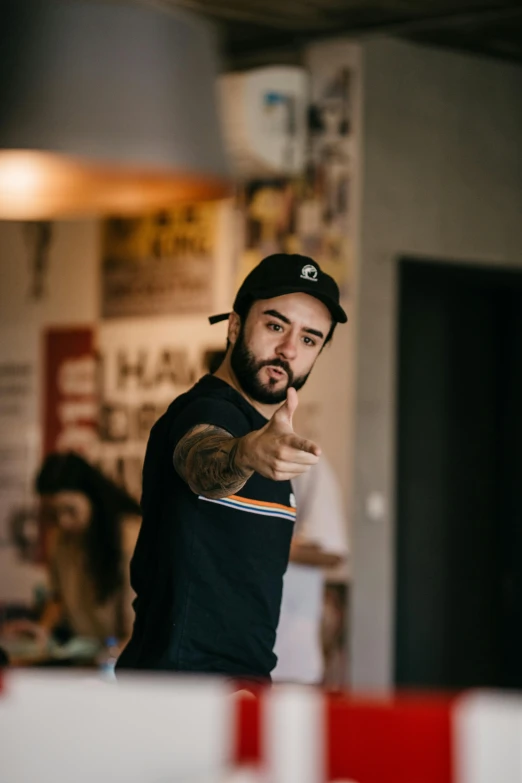 man wearing cap pointing finger towards camera while people look on