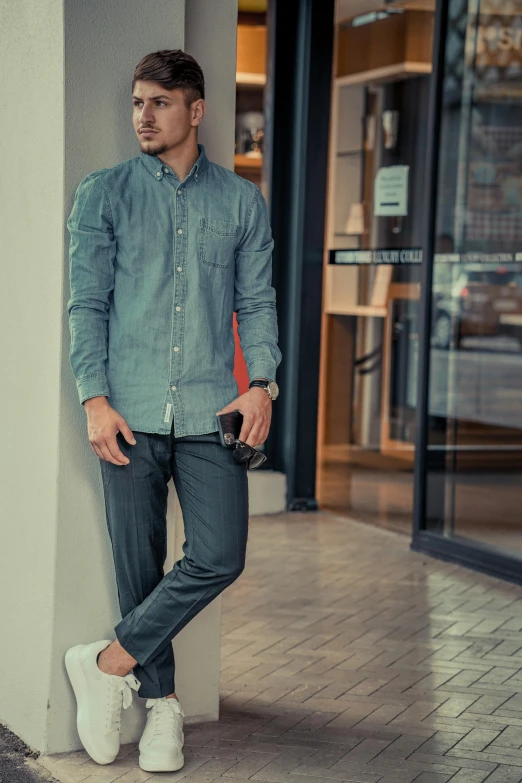 the young man is leaning against the building and posing for the camera