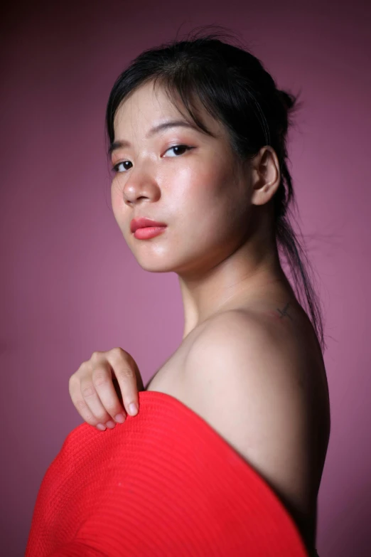 a  poses in a red top against a dark background