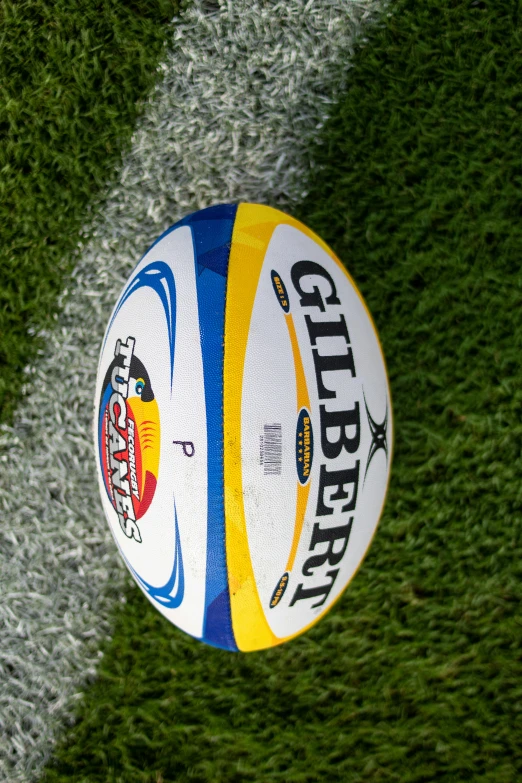 a white and yellow volleyball in grass at a stadium