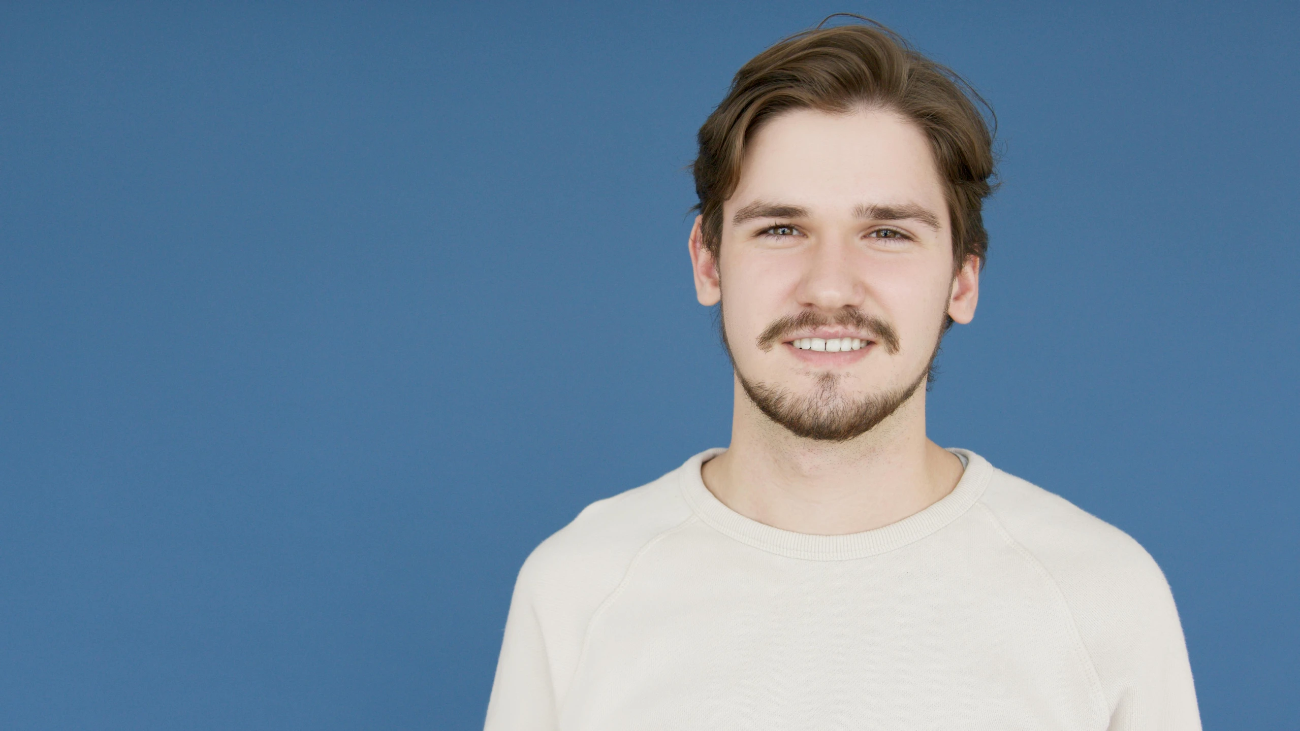 a man with beard smiles brightly at the camera