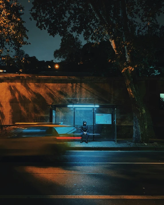 a man sitting on a bench alone near a tree at night