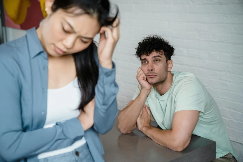 man sits with hand on face next to a woman