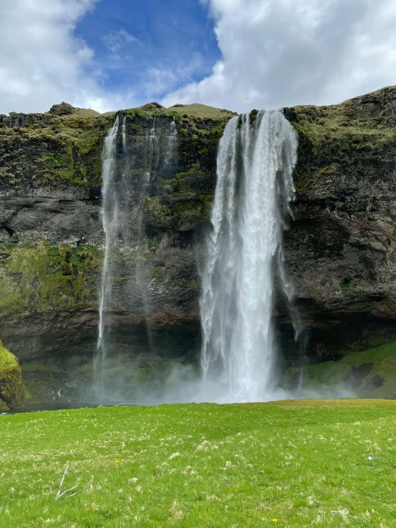 a large waterfall towering over a lush green field