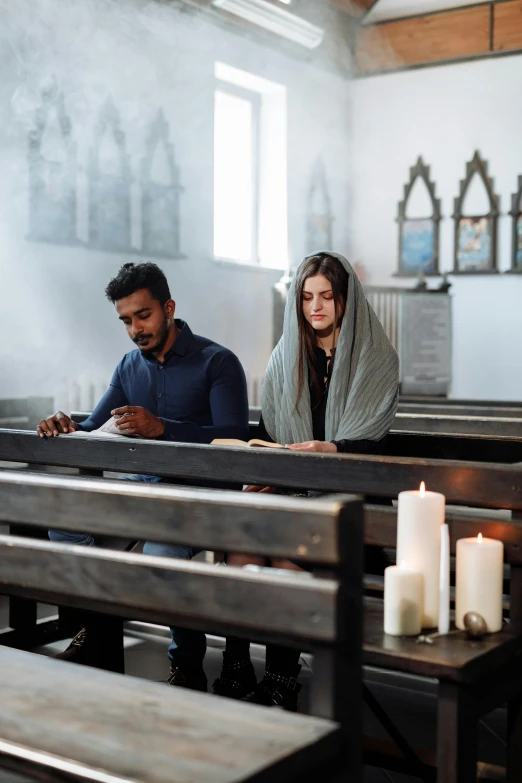 two people sitting at pews in a church, one is texting