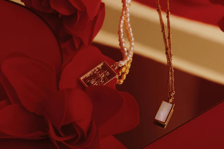 a necklace and a pearl necklace laying on a red fabric