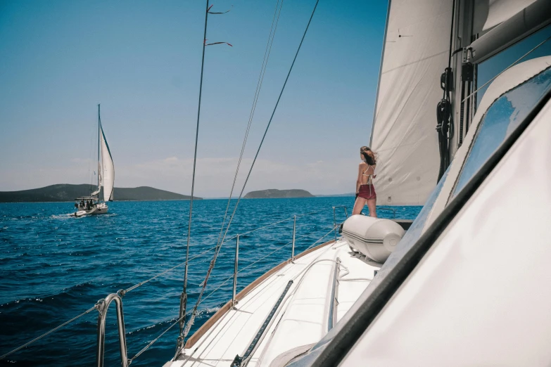 a woman in swimsuit riding a sailboat on the ocean