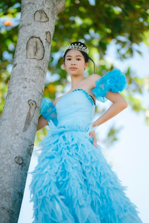 woman dressed in dress posing near tree in park