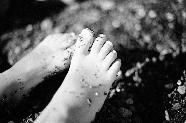 a person standing on a patch of stones with their feet covered in mud