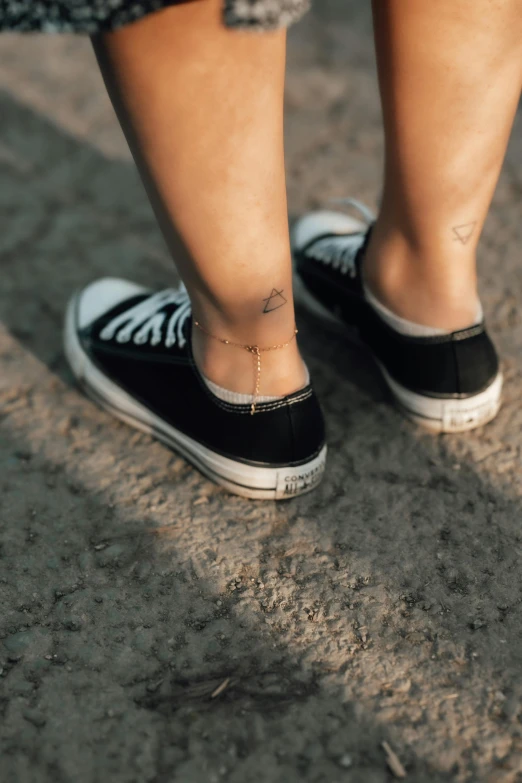 a person with an ankle tattoo standing in shoes