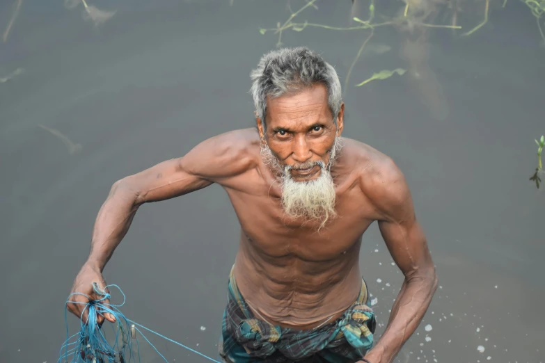 an old man wearing a blue cloth is by a body of water